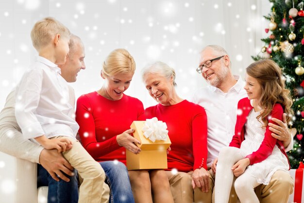 familie, vakantie, generatie, kerst en mensen concept - lachende familie met geschenkdozen die thuis op de bank zitten