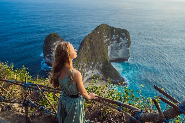 Familie vakantie levensstijl Gelukkige vrouw staan op uitkijkpunt Kijk naar prachtig strand onder hoge klif Reisbestemming op Bali Populaire plek om te bezoeken op het eiland Nusa Penida