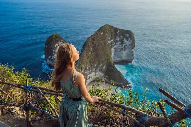 Familie vakantie levensstijl Gelukkige vrouw staan op uitkijkpunt Kijk naar prachtig strand onder hoge klif Reisbestemming op Bali Populaire plek om te bezoeken op het eiland Nusa Penida