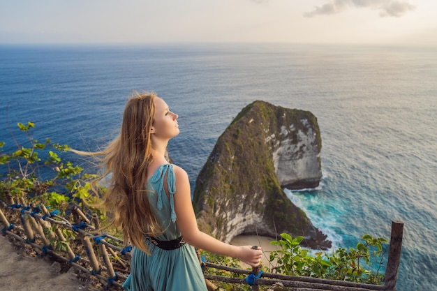 Familie vakantie levensstijl Gelukkige vrouw staan op uitkijkpunt Kijk naar prachtig strand onder hoge klif Reisbestemming op Bali Populaire plek om te bezoeken op het eiland Nusa Penida