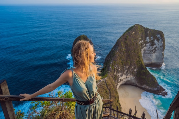 Familie vakantie levensstijl Gelukkige vrouw staan op uitkijkpunt Kijk naar prachtig strand onder hoge klif Reisbestemming op Bali Populaire plek om te bezoeken op het eiland Nusa Penida