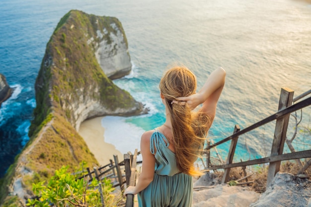 Familie vakantie levensstijl Gelukkige vrouw staan op uitkijkpunt Kijk naar prachtig strand onder hoge klif Reisbestemming op Bali Populaire plek om te bezoeken op het eiland Nusa Penida