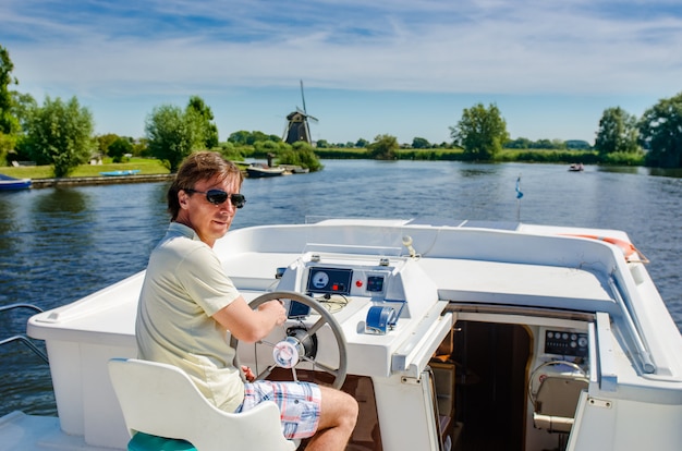 Familie vakantie, zomervakantie reizen op binnenschip in kanaal, man door stuur op riviercruise reis in woonboot in Nederland