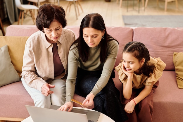 Familie van drie generaties die op uw gemak kleding bestellen in de online winkel