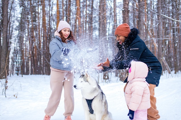 Familie van gemengd ras in trio die nieuwjaarsvakanties doorbrengen in het park met hun husky hond