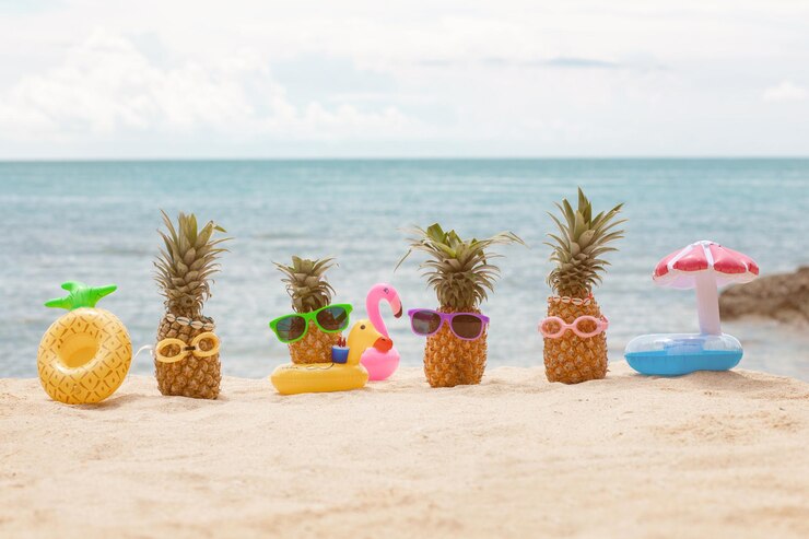 Familie van grappige aantrekkelijke ananassen in stijlvolle zonnebril op het zand tegen turquoise zee. Kerstmutsen dragen. Kerstmis en Nieuwjaar vakantie concept op tropisch strand. Vakantie met het gezin. Helder