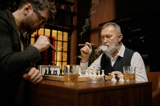 Familie van intelligente mensen die schaken, sigaren roken en whisky drinken