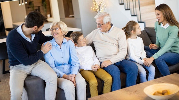 Familie van meerdere generaties die samen op de bank zitten in een modern huis en tv kijken