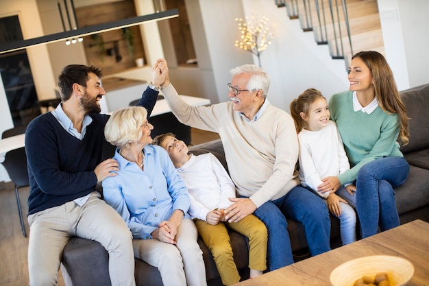 Familie van meerdere generaties die samen op de bank zitten in een modern huis en tv kijken