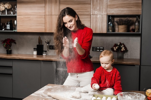 Familie van moeder en kind dochter spelen met meel en koken deeg samen voor het bakken van broodjes Moederschap Jonge moeder brengt tijd door samen met haar peuter