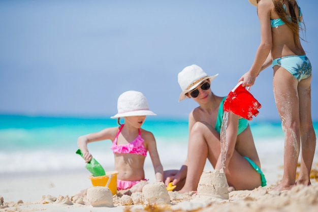 Familie van moeder en kinderen maken zandkasteel op tropisch strand