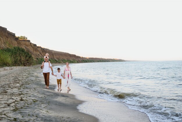 Familie van vier wandelen langs de kust, ouders en twee zonen, gelukkig vriendelijke familie