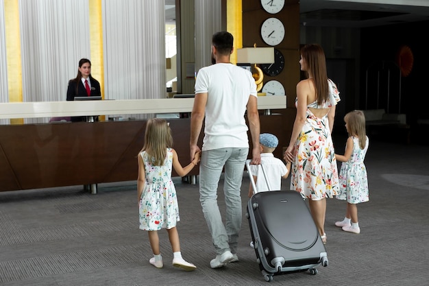 Familie van vijf gaat naar de lobby van het hotel om in te checken bij de receptie voor vakantie