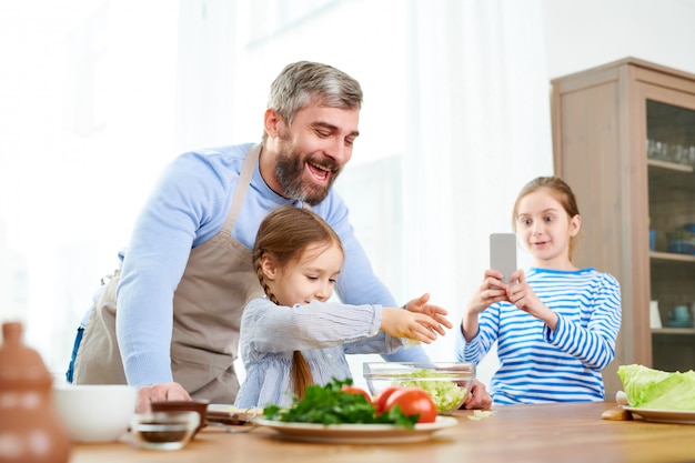 Familie van voedselbloggers die salade voorbereiden