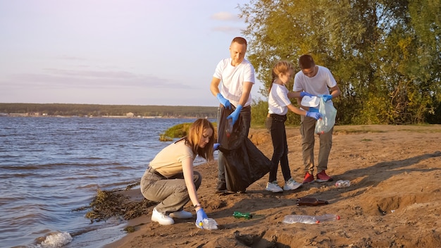 Familie verzamelt plastic afval in zakken bij de kust