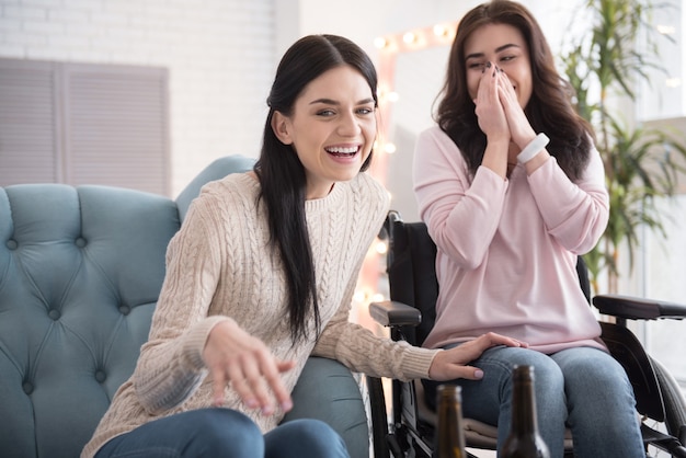 Familie vrijetijdsbesteding. Vrolijke zus en gehandicapte vrouw praten en lachen