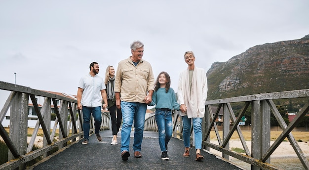 Familie wandelen en reizen met een meisje en grootouders hand in hand op een pier terwijl ze samen op vakantie of vakantie zijn Liefdesvertrouwen en kinderen met een man vrouw en kleindochter die een wandeling maken