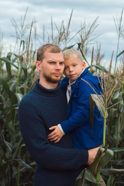 Familie wandelen in maïsveld bij herfst vader en zoon poseren tussen hoge planten