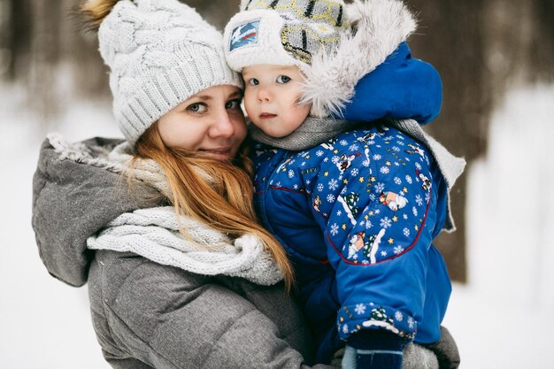 Familie wandeling door het winterbos Moeder en baby in de winter Moederschap Sneeuwvlokken vangen