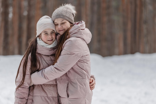 Familie winterwandeling in het bos Moeder en dochter hebben plezier in de winter in het bos bij zonnig ijzig weer Een moeders knuffel