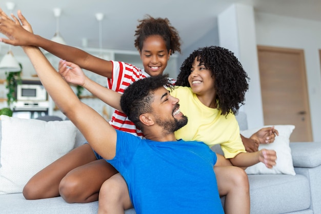 Familie zittend op de bank glimlachend naar de camera op de achtergrond van een modern appartement Gelukkig gezin met dochter die thuis speelt en in het weekend voor familie