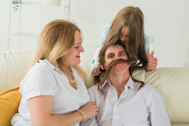 Familie zittend op de bank in hun woonkamer. Dochter heeft een blessure, maar ze is blij dat ze bij haar familie is.