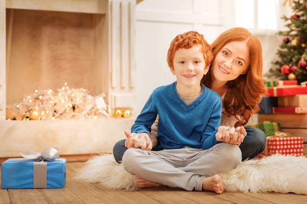 Familiebanden. Vrolijke familie zittend op de vloer terwijl ze thuis hun handen bij elkaar houden.