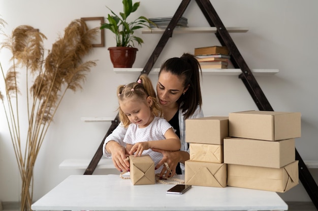 Familiebedrijf moeder en dochtertje zitten aan tafel omringd door dozen en bereiden samen de goederen voor op verzending