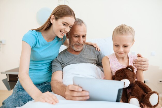 Familiebezoek aan bejaarde die tablet gebruikt