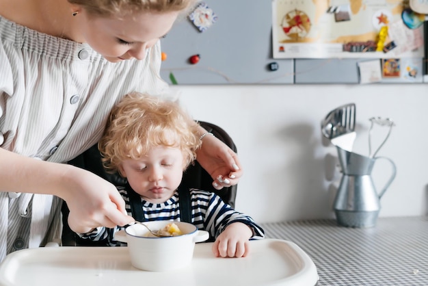 Familiediner moeder voedt haar zoon met heerlijke aromatische soep