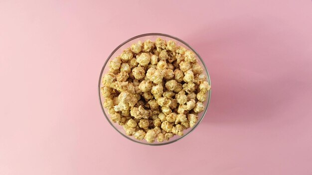 Familiehanden grijpen popcorn. Glazen ronde kom met zoete popcorn op gele achtergrond. bovenaanzicht.