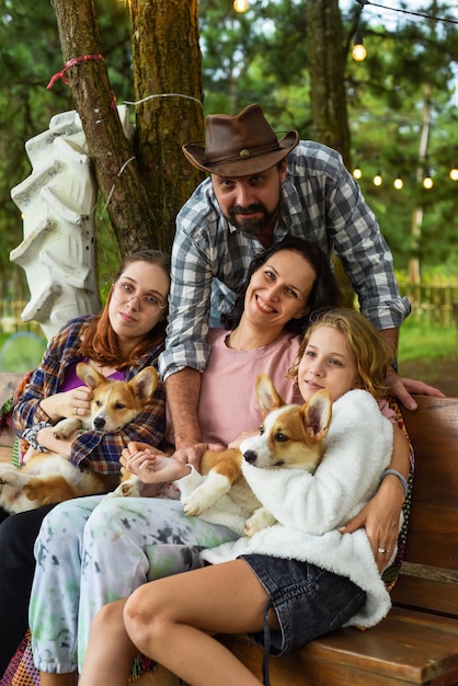 Familieleden vader moeder en twee dochters met corgi honden in het bos