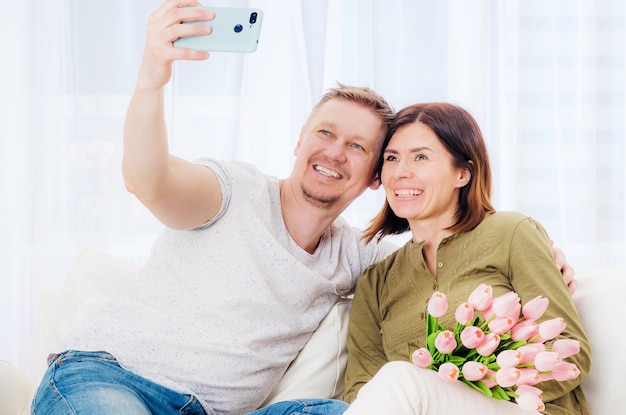 Familiepaar dat selfie met bloemboeket op mobiel neemt