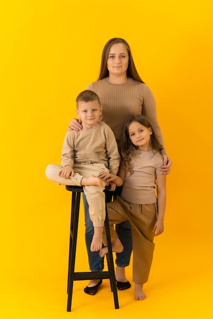 Familieportret van moeder dochter en zoon op een gele achtergrond in de studio