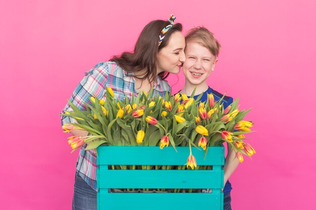 Familieportret zus en tienerbroer met tulpen op roze muur