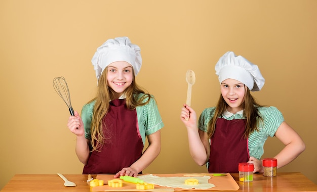 Familierecept Kookvaardigheid culinaire educatie Gemberkoekjes bakken Meisjes zusjes plezier gemberdeeg Zelfgemaakte koekjes het lekkerst Kinderen samen koekjes bakken Kinderschorten en koksmutsen koken