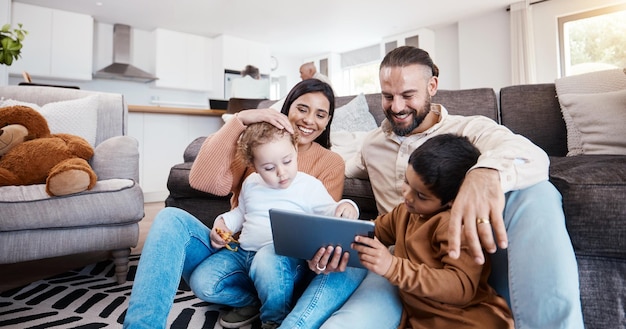 Familietablet en kinderen leren online in de woonkamer van hun huis met ouders voor de ontwikkeling van kinderen Onderwijsvideo of internet met een vader, moeder en kinderen die op de grond zitten
