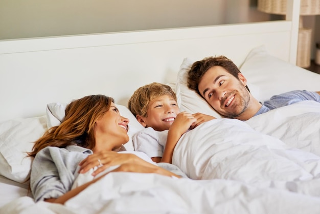 Familietijd in de ochtend maken shot van een vrolijk jong gezin dat overdag thuis in bed ontspant