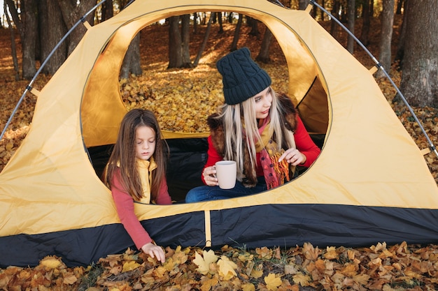 Familietoerisme in de herfst. Moeder en dochter genieten van kamperen in het bos.