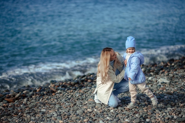 Familievakantie op zee in de herfst of lente Gelukkige familie moeder en dochter op een wandeling langs de kust