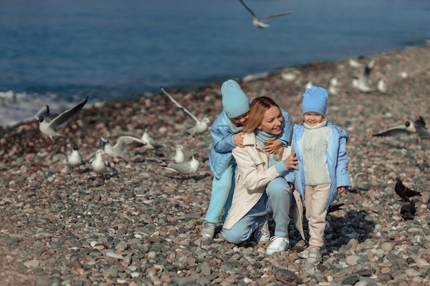 Familievakantie op zee in het laagseizoen gelukkige moeder en kinderen wandelen langs de kust