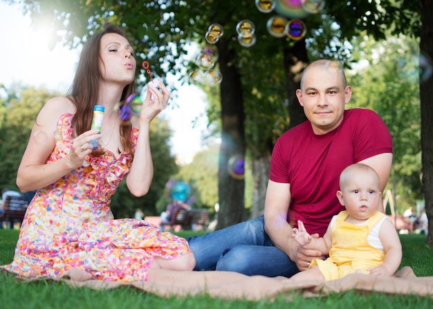 Familieweekend Moeder vader en zoon in een zomerpark zitten op een groen gazon