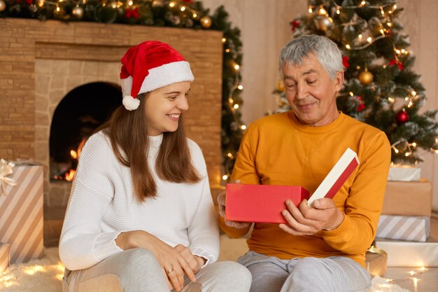 Familiezitting met hun grootvader die Kerstmis in gezellig huis viert