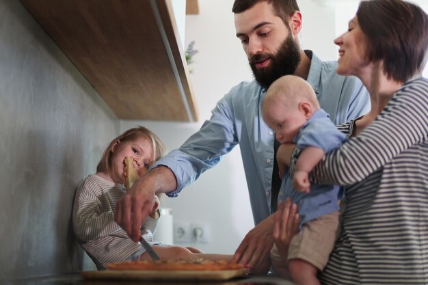 Family of 4 posing in the kitchen smiling and happy