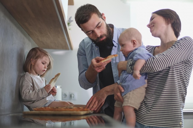 Family of 4 posing in the kitchen smiling and happy