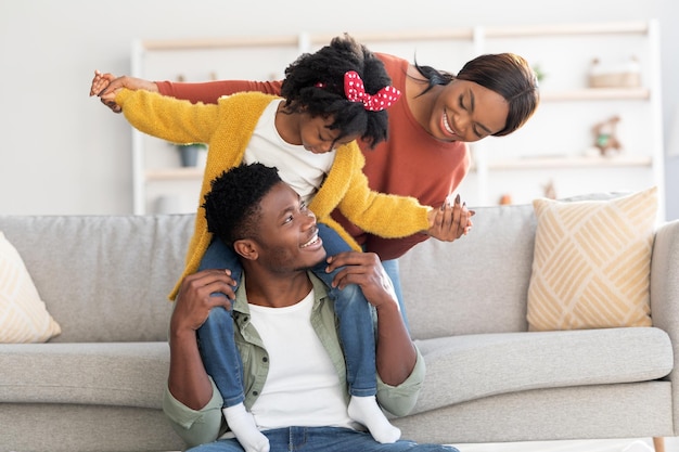 Family activities happy black parents having fun with little daughter at home