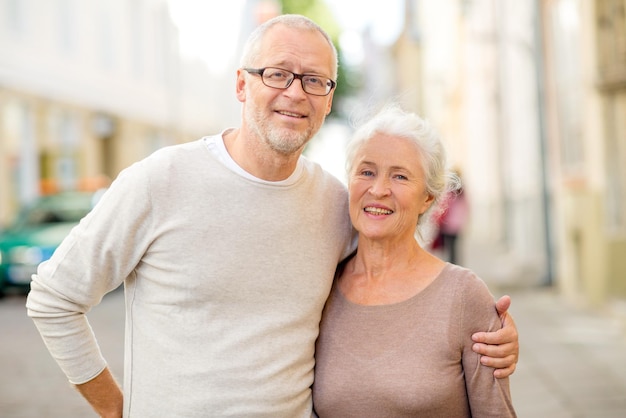 family, age, tourism, travel and people concept - senior couple hugging on city street