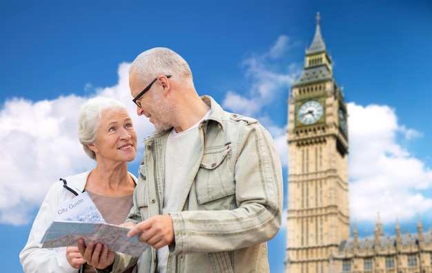 Concetto di famiglia, età, turismo, viaggi e persone - coppia senior con mappa sulla torre del big ben sullo sfondo della città di londra