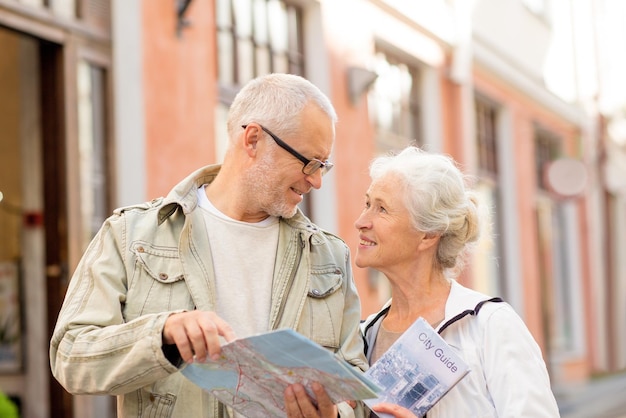 家族、年齢、観光、旅行、人々の概念-路上で地図とシティガイドを持つ年配のカップル