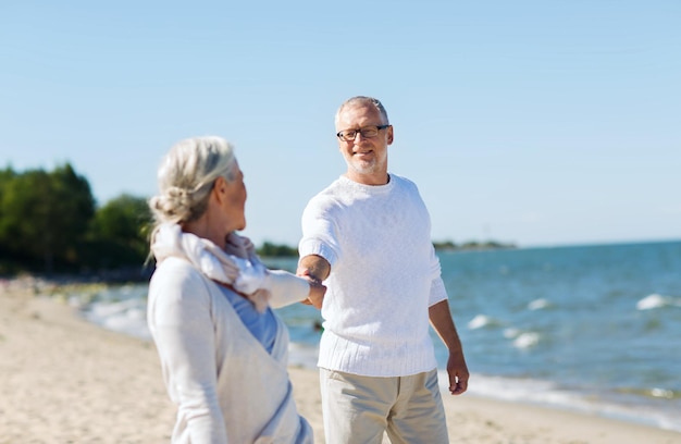 family, age, travel, tourism and people concept - happy senior couple holding hands on summer beach